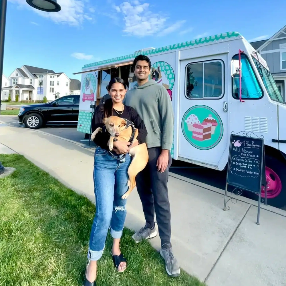 Dr. Dushyant Patel and his wife with their dog beside a local food truck.