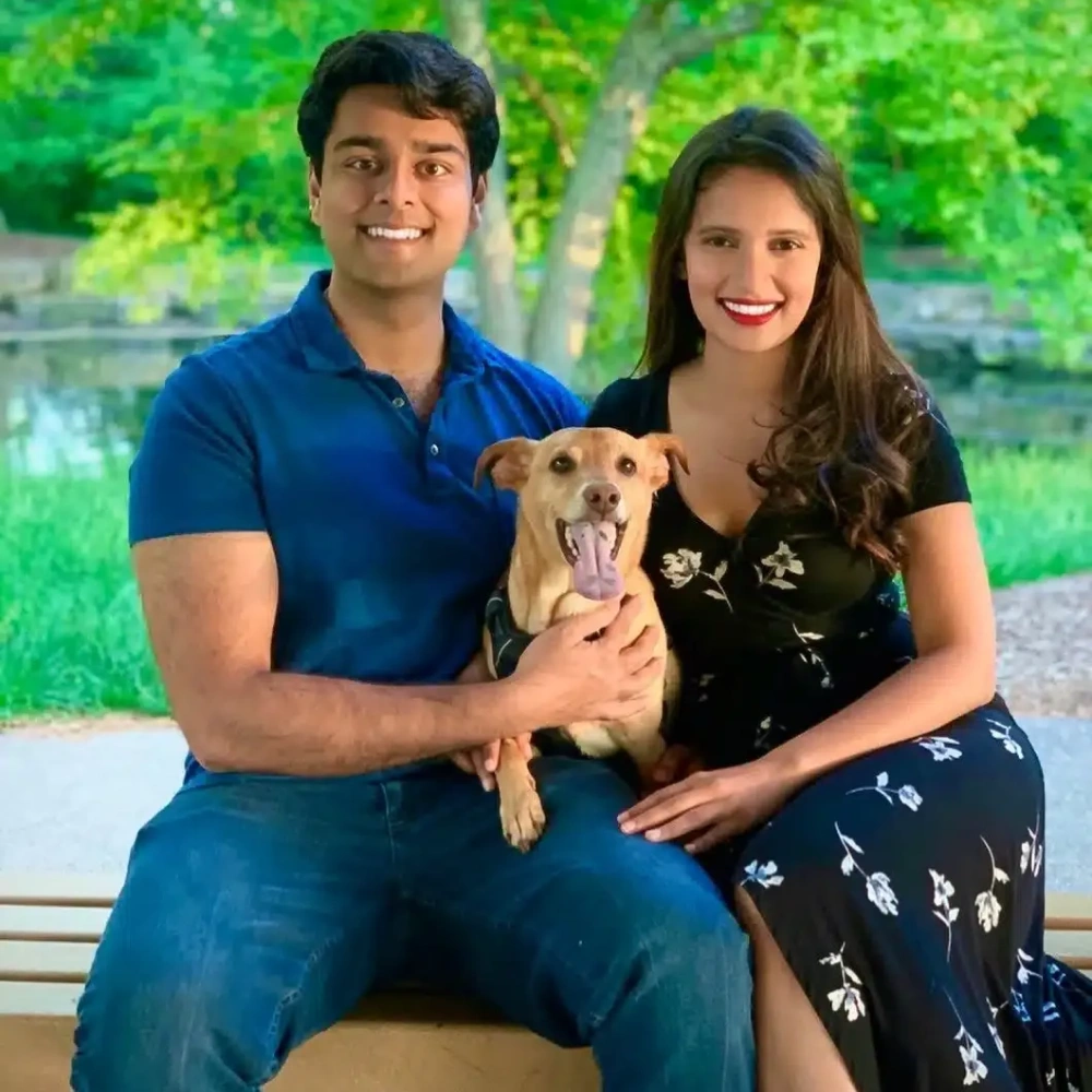 Dr. Dushyant Patel and his wife sitting outdoors with their dog.