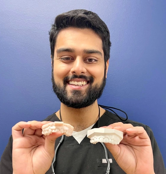 Dr. Patel holding dental veneer models to demonstrate custom veneer treatment options.