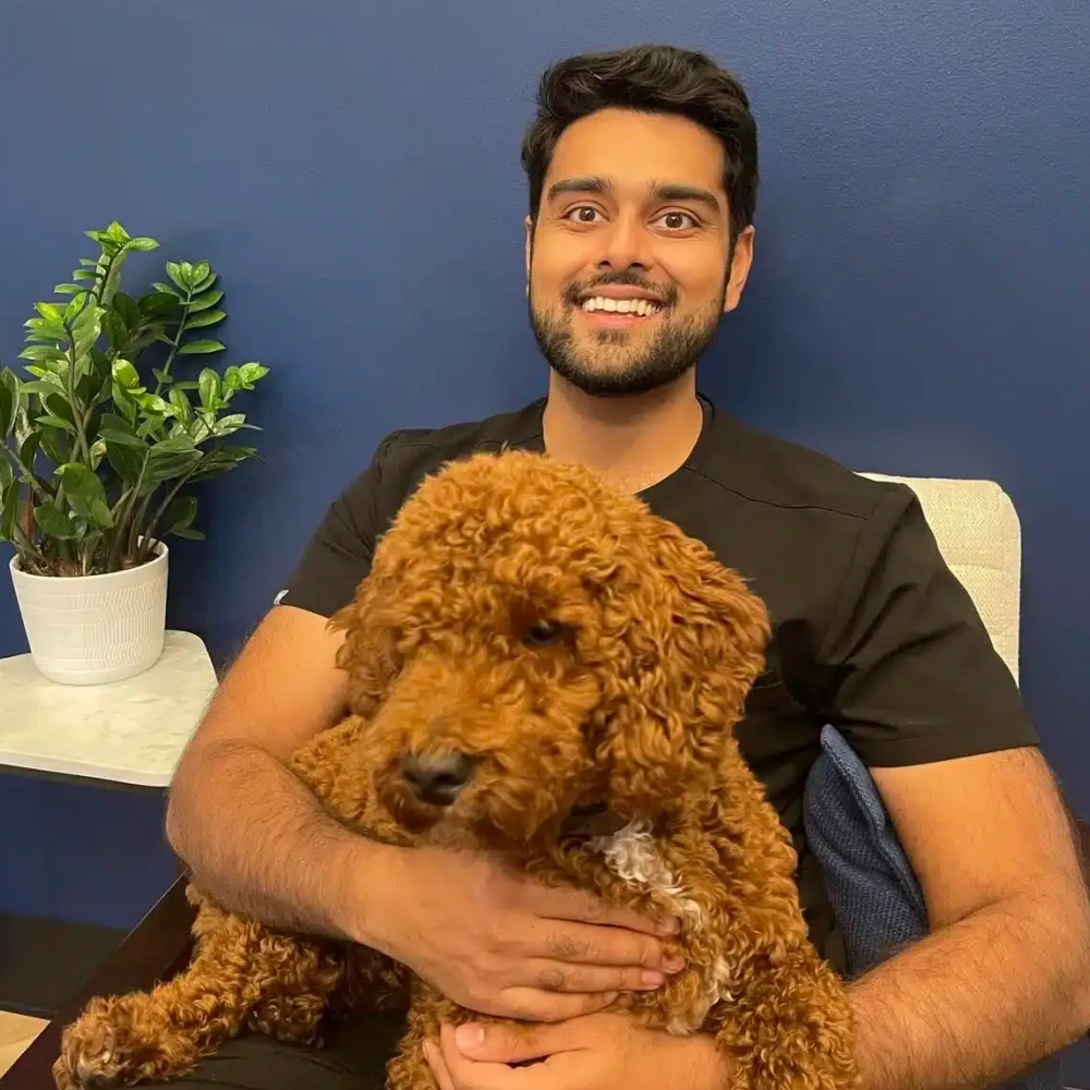 Dr. Dushyant Patel smiling while holding a friendly dog inside Sumner Dental Group.